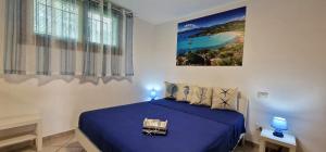 奥尔比亚La casa al mare, Pittulongu的卧室配有蓝色的床和墙上的绘画作品