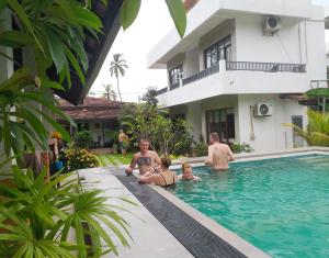 尼甘布内贡博绿树住宿加早餐旅馆的一群人在房子的游泳池里