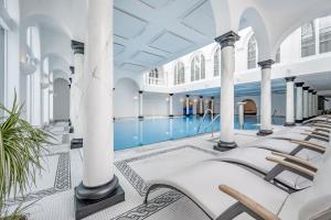 萨姆瑙恩Relais & Châteaux Chasa Montana的一座带白色柱子和椅子的建筑中的游泳池
