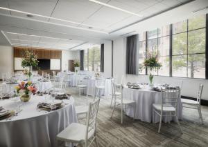 代顿AC Hotel by Marriott Dayton的一间设有白色桌子和椅子的房间,并鲜花