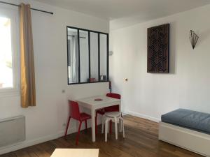 巴黎Studio perfect for 2 adults and 1 kid, and up to 2 kids - Jourdain 20e, 25mn to Louvre via line M11的配有桌子和两把椅子及一张床的房间