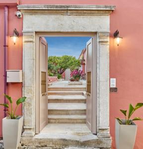阿卡尼斯Arhontiko Arhanes Suites的通往粉红色建筑的开放式门道,设有楼梯