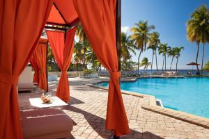 North StarCarambola Beach Resort St. Croix, US Virgin Islands的一个带橙色遮阳伞和水边桌子的游泳池