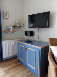 奥斯赛拜-屈隆斯博恩Yachthafenresidenz-Wohnung-8205-853的一间设有蓝色橱柜的客房,墙上配有电视