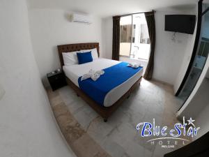 梅尔加Blue Star Hotel的一间卧室配有一张带蓝色床单的床和一扇窗户。