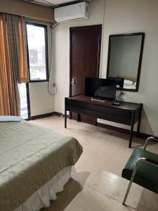 瓜亚基尔里佐酒店的一间卧室配有一张床和一张书桌及电视