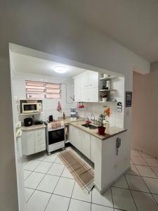 瓜鲁雅Nosso apê no Guarujá - Unidade Aquário的厨房配有白色橱柜和白色瓷砖地板。