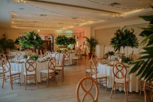 曼努埃尔安东尼奥Parador Nature Resort and Spa的宴会厅配有白色的桌椅和植物