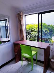 LimbeChinyonga Guesthouse的窗户前的一张带绿椅的桌子