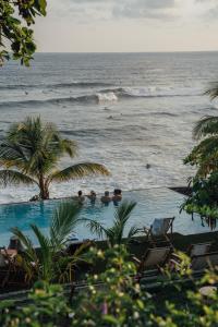 埃尔蒙特Puro Surf Hotel的毗邻大海的游泳池,里面的人