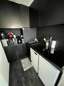 多维尔Un été sans fin à Deauville的一间小厨房,配有黑色的墙壁和白色的橱柜