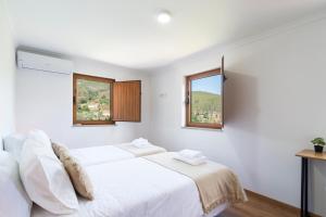 VideNEW - Casa das Domingas的一间白色卧室,配有床和2个窗户