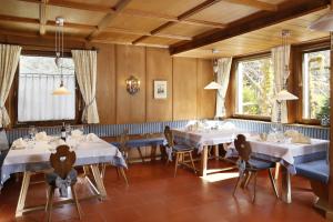 拉古多Parkhotel Tirolerhof的一间设有白色桌椅和窗户的用餐室
