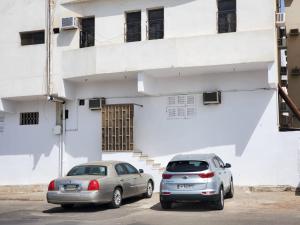 麦地那شقة جمان طيبة Joman Taibah Apartment的两辆汽车停在白色建筑前面