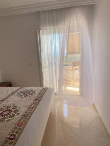 拉巴特Nice apartment beach front, close to Rabat main sightseeing. Fiber WiFi的一间卧室配有一张床和一个带椅子的窗户