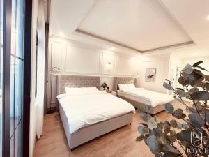 大叻Joyce Boutique Coffee & Stay的一间卧室配有两张带白色床单和植物的床。
