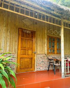 宁平Ninh Binh Bamboo Farmstay的木门和门廊上的长凳的房子