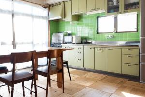由布市【湯布院の山小屋】サンクラウド・ヒュッテ的厨房配有木桌和绿色瓷砖