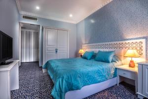 巴库尊贵老门酒店的一间蓝色的卧室,配有一张床和一台电视