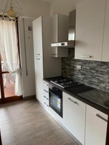 罗马Eur Centro lux apartment con camino的厨房配有白色橱柜和炉灶烤箱。