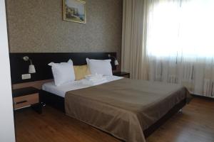 普洛耶什蒂Hotel Nord的卧室配有带白色枕头的床和窗户。