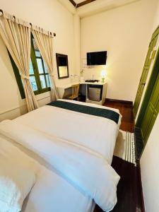 琅勃拉邦Barn Laos Luangprabang Hostel的一间卧室配有两张白色的床和电视