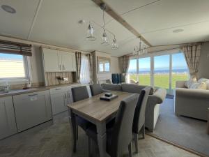 Hopton on SeaLuxury Lodge With Stunning Full Sea Views In Suffolk Ref 20234bs的厨房以及带桌椅的用餐室。