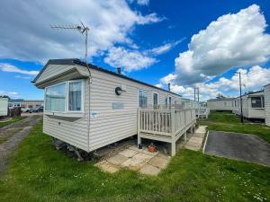 赫彻姆Lovely 6 Berth Caravan With Decking To The Side In Heacham Ref 21009i的一间小白色房子,在草地上设有门廊