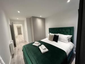 坎伯利Mustafa House By E2M Stays - 1 & 2 Bedroom Stunning Apt in Central Town的一间卧室配有绿床和2条毛巾