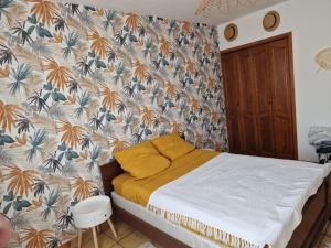 维亚斯La Maison de Léonie sur Vias的一间卧室配有一张带花卉壁纸的床