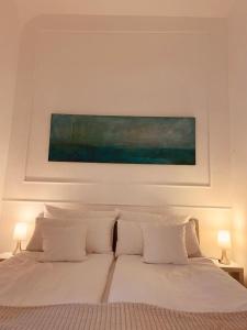 多特蒙德Apartment 229的一张带白色枕头的床和上面的绘画