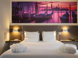 鲁瓦西昂法兰西诺富特套房酒店 - 巴黎戴高乐机场维勒班的酒店客房的墙上设有一张带照片的床。