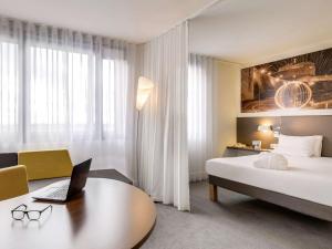 鲁瓦西昂法兰西诺富特套房酒店 - 巴黎戴高乐机场维勒班的酒店客房配有一张床、一张书桌和一台笔记本电脑