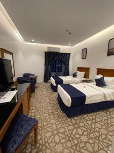 Abū Qa‘arAl Farhan Hotel & Suites Hafr Al Batin的一间酒店客房,设有三张床和一台平面电视