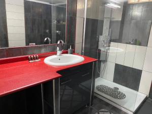 埃泽萨Luxury Apartment in the center的一间带红色柜台、水槽和淋浴的浴室