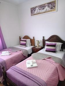 圣地亚哥-杜卡森Alojamento Local Largo da Igreja的配有紫色和白色床单的客房内的两张床