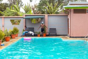 阿鲁沙Okaseni Lodge的站在游泳池旁的人