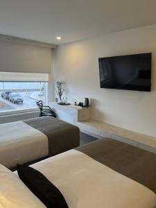 纳塔列斯港Hotel Costanera的酒店客房设有两张床和一台平面电视。