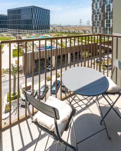 迪拜First Class 1BR Apartment in Dubai Hills - next to Dubai Hills Mall的阳台配有桌椅,享有停车场的景致