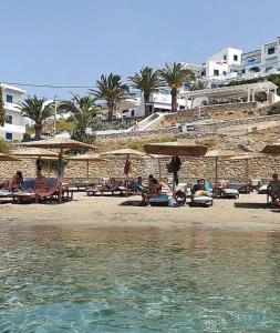 卡尔帕索斯Grannys Luxury Villas的一群人坐在海滩上,拿着遮阳伞