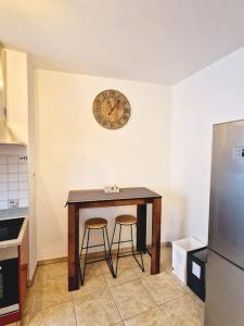 戈尔多拉Appartamento 4.5 - Gordola的厨房配有一张桌子、两张凳子和墙上的时钟