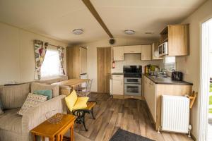 亨斯坦顿Beautiful Caravan With Decking At Wifi At Manor Park, Hunstanton Ref 23098t的带沙发的客厅和厨房