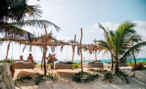 图卢姆GlampIKAL formerly Casa Nawal的海滩上,有椅子和棕榈树,还有大海