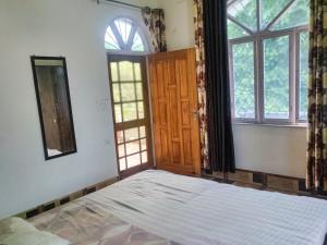 德拉敦Gaharwar Home Stay的一间空卧室,配有床和2个窗户