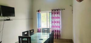 德拉敦Gaharwar Home Stay的一间设有玻璃桌和窗户的用餐室