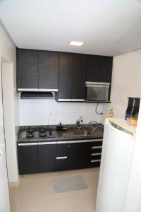 帕尔马斯AP 104-A Térreo Completo Aconchegante的厨房配有黑色橱柜和水槽