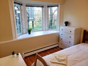 温哥华Bright Garden Suite by the Beach and UBC的一间卧室设有窗户、一张床和一个梳妆台