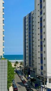 大普拉亚Apto ótima localização a 100m da Praia, Piscina, Ar Condicionado, Garagem e Portaria 24h的海滩旁一座大型建筑,有汽车停放