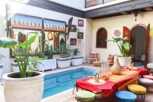 马拉喀什RIAD KECHMARA的庭院设有游泳池和植物桌子