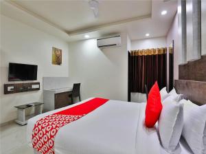 德瓦尔卡The Sky Comfort Hotel Parth Inn的卧室配有带红色枕头的大型白色床
